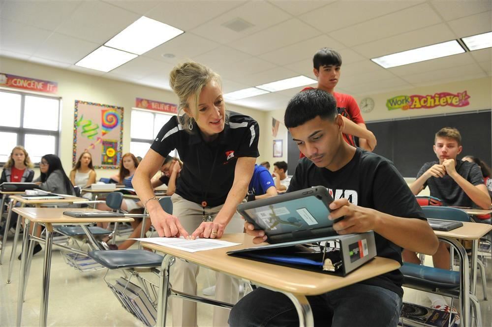 teacher helping student at desk