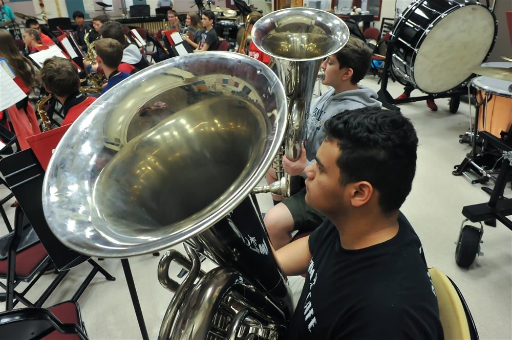 Student holding an instrument while seated.